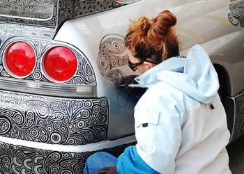 Un homme laisse sa femme artiste dessiner avec un stylo feutre sur sa Nissan Skyline GTR