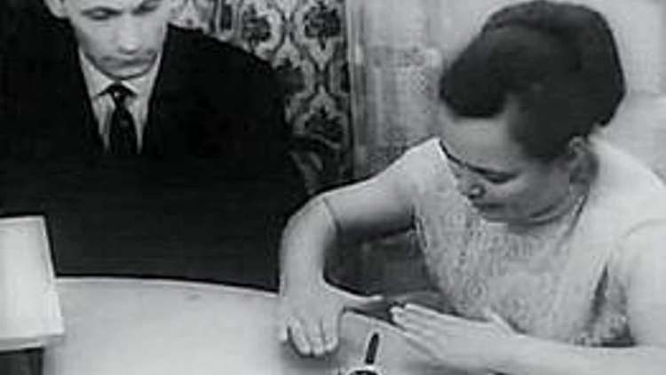 Une femme participant à une expérience de télékinésie en laboratoire, se concentrant sur un objet sous cloche.