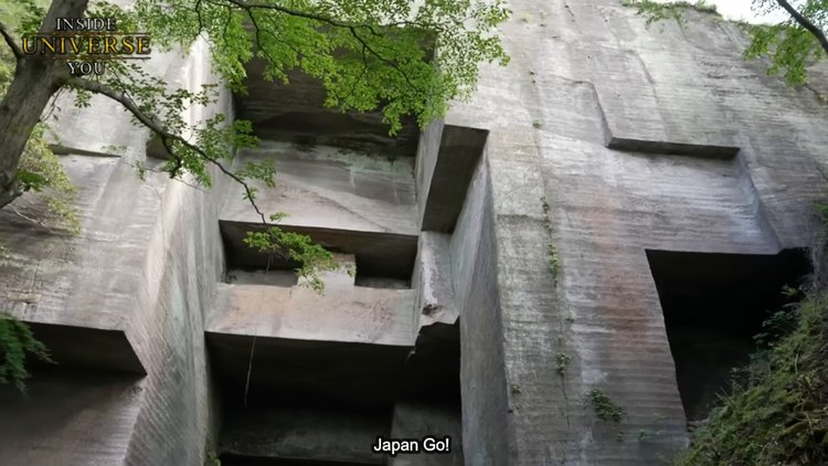 Vue rapprochée d'une paroi de pierre taillée avec des marques régulières.