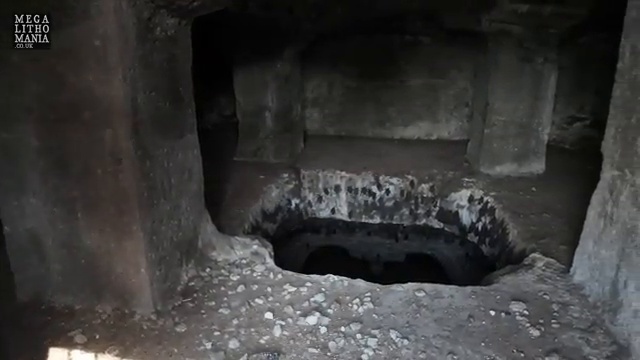 Gros plan sur une cavité profonde et sombre dans le sol, témoignant des mystérieux espaces creusés dans la structure rocheuse.