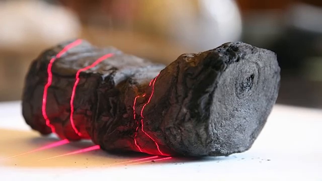 Gros plan sur un rouleau d'Herculanum carbonisé, scanné par des lasers rouges pour tenter de le lire sans l'ouvrir.