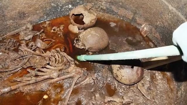 Vue à l'intérieur du sarcophage noir d'Alexandrie, montrant des squelettes immergés dans des eaux usées rougeâtres.