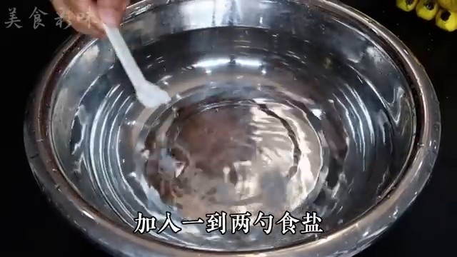 Lavage de la grappe de bananes dans une bassine d'eau salée