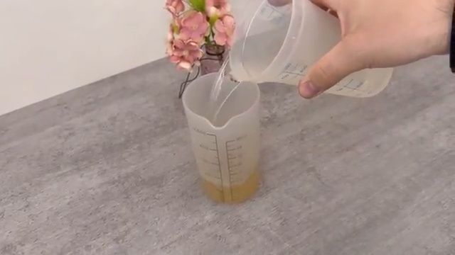 Ajout de l'eau dans le gobelet doseur contenant le vinaigre