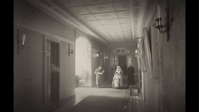 Couloir long et lumineux d'un établissement hospitalier avec des portes et des tableaux.