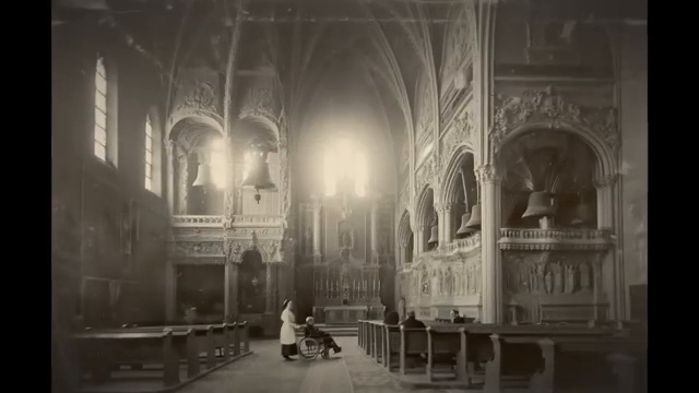 Intérieur d'une salle avec des cloches visibles sur les côtés et des personnes assises.