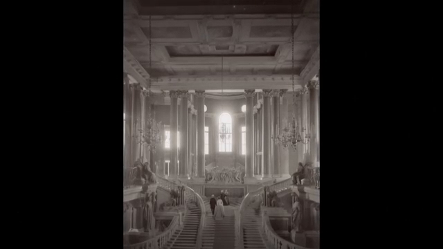 Escalier monumental éclairé par une grande fenêtre centrale, soulignant la grandeur des bâtiments détruits.