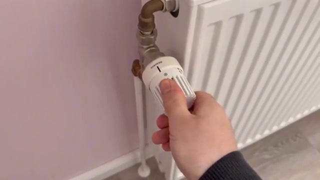 Main tournant la vanne thermostatique du radiateur sur la position 5