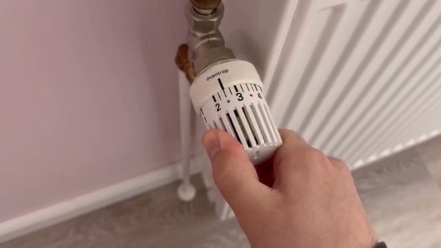 Doigt montrant les petites lignes d'incrémentation situées entre les numéros principaux du thermostat